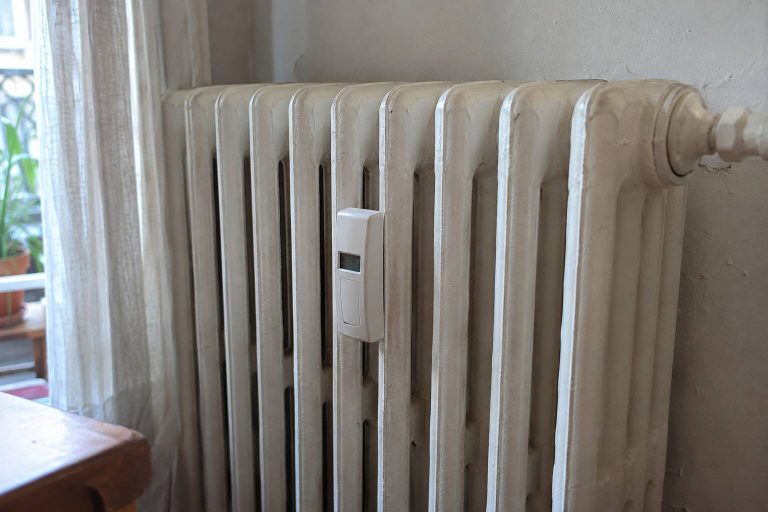 Radiateur en fonte blanche muni d'un petit thermostat